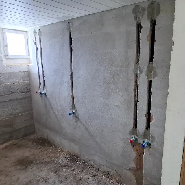 Salle de bain en travaux : alimentations sanitaires encastrées dans le mur avant carrelage